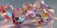 Heart-shaped pink crystal gemstones with rainbow reflections on gray background, creating romantic atmosphere for jewelry design or Valentine's Day concept.