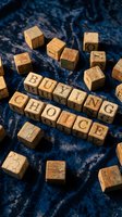 Wooden letter blocks spelling "buying choice" arranged on textured blue fabric with scattered cubes, representing consumer decisions and market selection for business concepts.