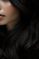 Close-up of smooth, glossy dark hair flowing beside woman's face with soft skin and subtle lips, ideal for beauty and haircare advertising.