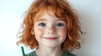 Young redhead child with curly hair and freckles smiling at camera against white background. Happy kid portrait for family, childhood, education concepts.