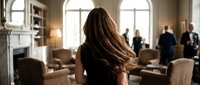 Professional businesswoman with long brown hair in elegant office meeting room with colleagues discussing strategy in corporate environment.