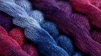 Colorful knitted fabric texture in blue, purple and red tones showing detailed wool or yarn pattern with wavy lines and soft material structure. Close up macro shot.