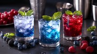 Colorful summer cocktails with fresh berries and mint garnish on dark background. Refreshing drinks with ice cubes, blueberries and raspberries for bar menu.