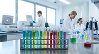 Scientists conducting colorful chemical experiments in modern laboratory with test tubes containing vibrant solutions for research and analysis.