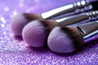 Professional makeup brushes with soft bristles on purple glitter background, close-up macro shot showing texture and detail for cosmetics and beauty industry.