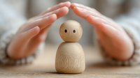Hands protecting wooden figurine with simple face, symbolizing care, support and nurturing in human relationships.