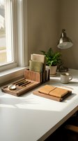 Cozy home office workspace with wooden desk organizer, leather notebook, coffee mug and green plant by window with natural sunlight for productivity.