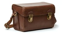 Vintage brown leather camera case with brass buckles and adjustable strap isolated on white background for retro photography equipment storage.