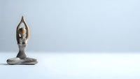 Minimalist bronze figurine in meditation pose with raised arms on clean white surface against neutral background for wellness and mindfulness concepts.