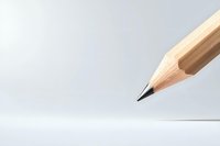 Sharp wooden pencil tip pointing downward against light gray background, minimalist composition with dramatic angle and shallow depth of field.