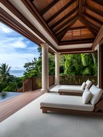 Luxury tropical resort terrace with wooden ceiling beams, white lounge chairs, infinity pool and ocean view for vacation and hospitality design.