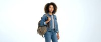 Young woman with curly dark hair and medium brown skin tone wearing denim jacket and jeans, carrying brown leather backpack. Casual fashion and lifestyle.