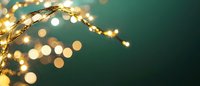 Glowing fairy lights create magical bokeh effect against dark green background, curved decorative wire with warm golden illumination for festive mood.
