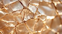 Metallic gold crumpled foil texture with geometric pattern and shiny reflective surface creates abstract luxury background with light and shadow play.
