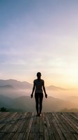 Woman in athletic wear standing on wooden platform overlooking misty mountain landscape at sunrise, conveying wellness, mindfulness and outdoor fitness lifestyle.