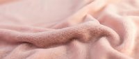 Soft pink fleece fabric with gentle folds and wrinkles creating cozy texture for comfort and warmth in home decor and fashion applications.