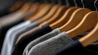 Wooden hangers with gray and black clothing in closet, selective focus on garment textures creates minimalist wardrobe composition for fashion and retail concepts.