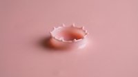 Liquid splash creating crown-like formation in soft pink tones, isolated on matching background, suitable for cosmetics, skincare, and beauty product packaging design.