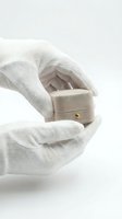 Hands wearing white cotton gloves holding open a beige velvet jewelry box with gold clasp against white background, suitable for luxury retail, engagement rings, and jewelry marketing.