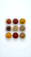 Colorful spices and seasonings arranged in glass bowls on white background for culinary cooking and food preparation projects.