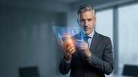 Mature Caucasian businessman in suit using futuristic transparent tablet with glowing interface in modern office environment for digital transformation concepts.