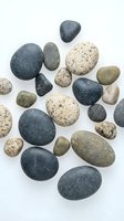 Collection of smooth river rocks and pebbles in natural colors isolated on white background for spa wellness meditation and decorative design projects.