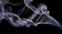 Colorful iridescent smoke swirls gracefully against a dark black background, creating an abstract, ethereal effect with rainbow hues.