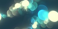 Dreamy turquoise and white bokeh lights create soft glowing circles against dark background, abstract defocused pattern for creative design projects and backgrounds.
