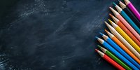 Colorful wooden pencils arranged diagonally on dark chalkboard background with copy space, perfect for education and back to school concepts.