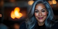 Confident mature Asian woman with trendy blue-gray hair smiling warmly at camera, soft evening bokeh lights creating cozy atmosphere in background.