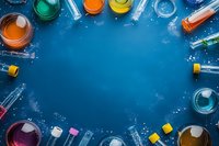 Colorful laboratory glassware and test tubes with vibrant liquids arranged in circular frame on dark blue background with copy space for science concepts.