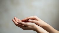 Open cupped hands in gentle receiving gesture against soft neutral background for prayer meditation and spiritual wellness concepts.