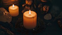 Warm glowing candles create cozy autumn atmosphere with dried leaves and natural decorations for seasonal home decor and relaxation ambiance.