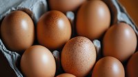 Fresh brown chicken eggs with water droplets in gray cardboard egg carton, close up view showing natural texture and condensation on shells.