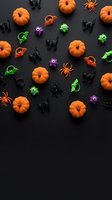 Halloween party decorations with orange pumpkins, spiders, black cats and colorful monsters scattered on dark background for seasonal celebration design.