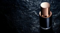 Luxury black and rose gold cosmetic bottle on dark stone background with dramatic lighting, minimalist premium skincare packaging design for beauty products.