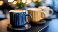 Steaming hot coffee in a dark blue ribbed ceramic mug with saucer, warm bokeh lights in background, cozy cafe atmosphere for beverage and lifestyle content.