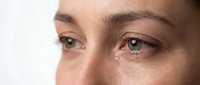 Close-up of woman's eyes with tears, showing emotional expression and natural skin texture. Concept for mental health, sadness, and human emotions.