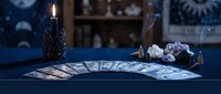 Mystical tarot card reading setup with burning candle, crystals and incense creating atmospheric fortune telling scene for spiritual guidance and divination practices.