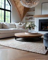 Modern living room with vaulted wood ceiling, white sofa, round coffee table and crystal chandelier. Neutral contemporary interior features fireplace, built-in shelving and natural textures.