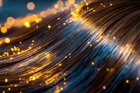 Glowing fiber optic cables with golden bokeh lights creating waves of blue and orange illumination against dark background, modern technology concept.