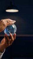 Hands holding glowing crystal ball with digital network connections inside, representing global communication and future technology concepts.