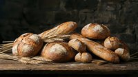 Assorted freshly baked artisan breads and rolls with wheat stalks arranged on rustic wooden surface against dark background for bakery and food styling.