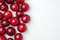 Fresh ripe cranberries arranged on white background with copy space. Bright red berries create natural border pattern for seasonal food design.