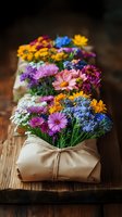 Colorful blooming flowers arranged in kraft paper wrapping with twine on wooden surface, featuring vibrant daisies, chrysanthemums and mixed seasonal blooms for floral design and gift presentations.