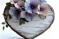 Rustic heart-shaped wicker basket decorated with purple hibiscus flowers on white wooden background for romantic decor and craft projects.