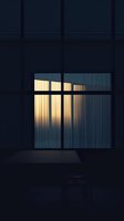 Warm light streaming through window with curtains in dark room creates moody atmosphere. Minimalist composition with strong contrast between darkness and illumination.