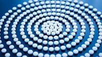 White spheres arranged in concentric circles creating hypnotic spiral pattern on blue background for modern design projects and digital art applications.