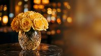 Golden yellow roses arranged in crystal cut glass vase on marble surface with warm bokeh lights creating elegant romantic atmosphere for luxury home decor.