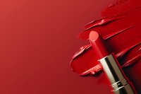 Red lipstick smeared on red background creating artistic makeup texture, cosmetic product photography for beauty and fashion industry advertising.